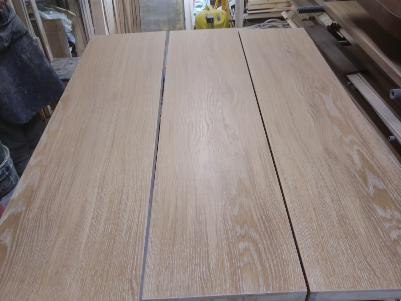 Серия длинных деревянных деталей на сборочном столе в мастерской